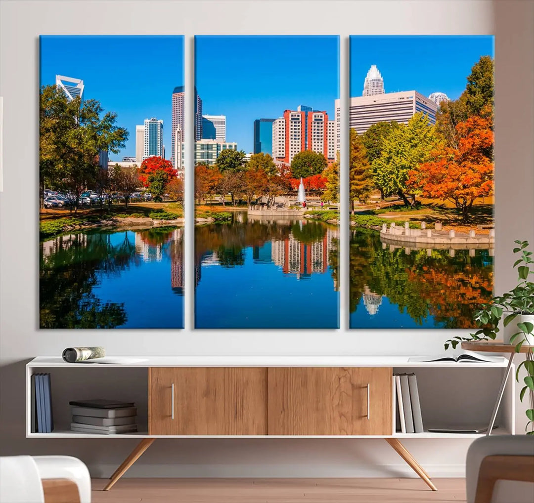 The "Charlotte City Autumn Morning Blue Skyline Cityscape View Wall Art Canvas Print" showcases a cityscape with vibrant autumn trees reflected in a lake. Its gallery-wrapped edges add depth to the scene, while the UV-protective coating ensures lasting brilliance.