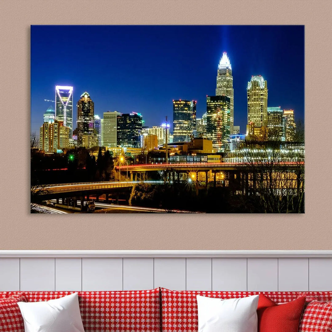 The Charlotte City Lights Night Blue Skyline Cityscape View Wall Art Canvas Print, showcasing an illuminated city skyline at night, is printed on museum-quality canvas with a UV-protective coating. Enhance your space with this stunning piece and enjoy free shipping with your purchase.