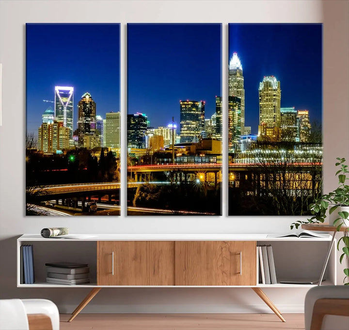 The Charlotte City Lights Night Blue Skyline Cityscape View Wall Art Canvas Print, showcasing an illuminated city skyline at night, is printed on museum-quality canvas with a UV-protective coating. Enhance your space with this stunning piece and enjoy free shipping with your purchase.