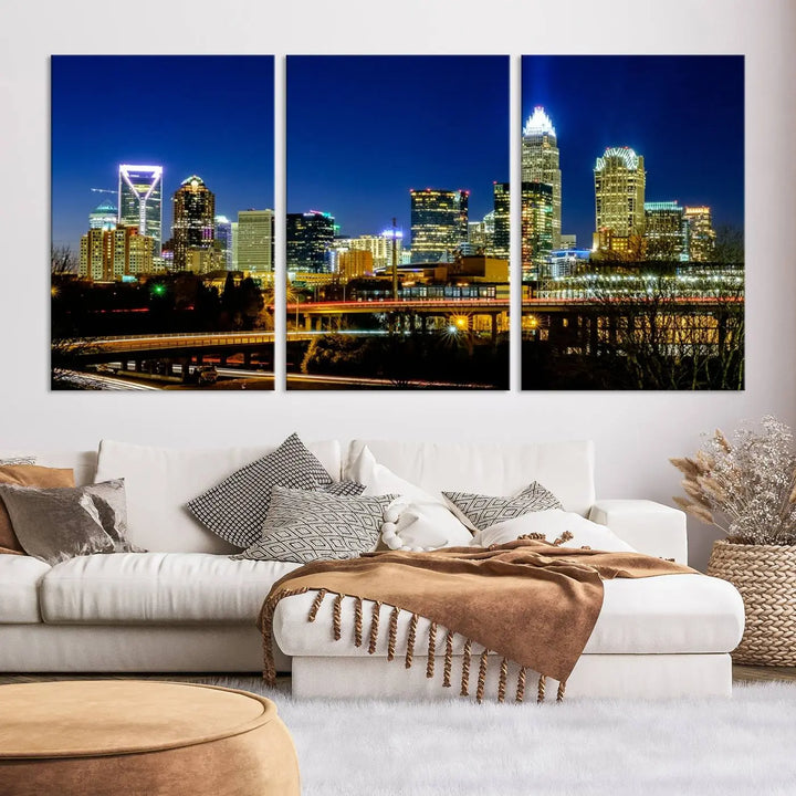 The Charlotte City Lights Night Blue Skyline Cityscape View Wall Art Canvas Print, showcasing an illuminated city skyline at night, is printed on museum-quality canvas with a UV-protective coating. Enhance your space with this stunning piece and enjoy free shipping with your purchase.