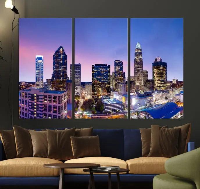 The Charlotte City Lights Sunset Purple Skyline Cityscape View Wall Art Canvas Print showcases a triptych of a city skyline with illuminated skyscrapers at dusk.