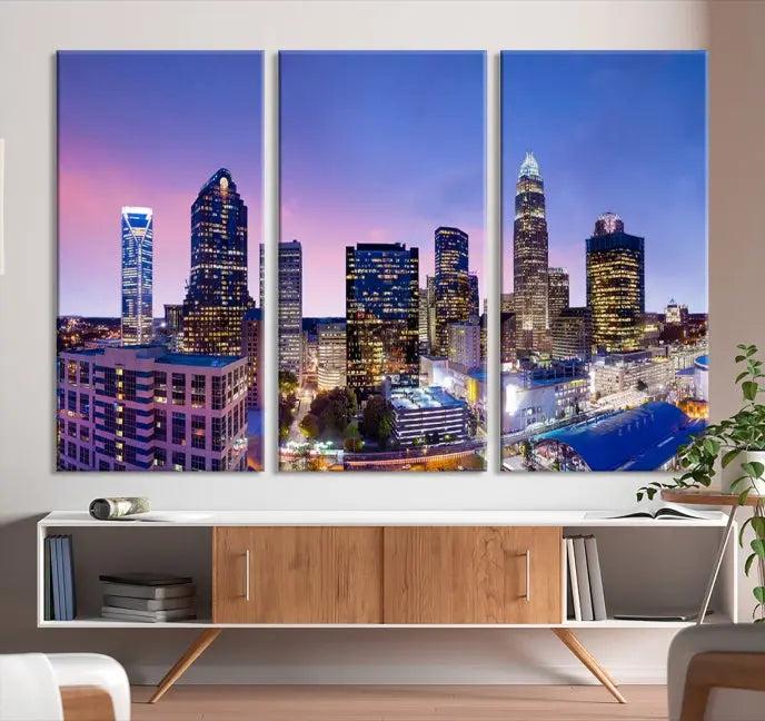 The Charlotte City Lights Sunset Purple Skyline Cityscape View Wall Art Canvas Print showcases a triptych of a city skyline with illuminated skyscrapers at dusk.