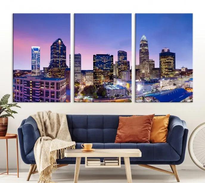 The Charlotte City Lights Sunset Purple Skyline Cityscape View Wall Art Canvas Print showcases a triptych of a city skyline with illuminated skyscrapers at dusk.