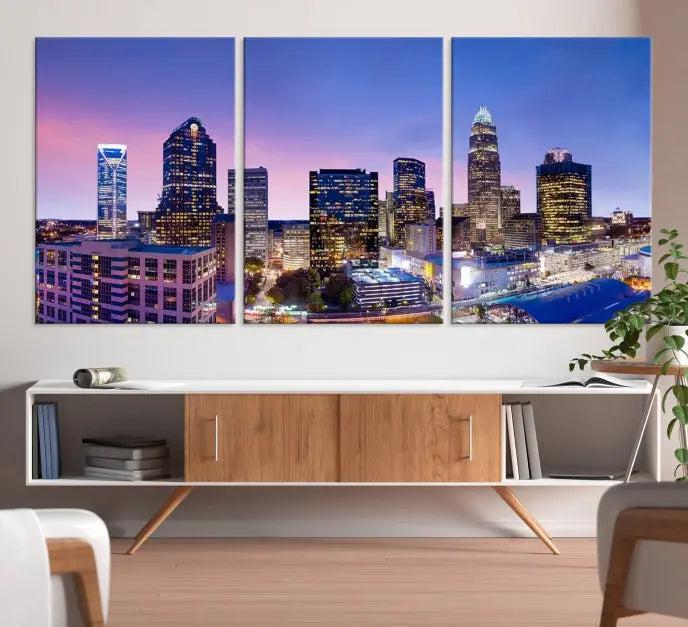 The Charlotte City Lights Sunset Purple Skyline Cityscape View Wall Art Canvas Print showcases a triptych of a city skyline with illuminated skyscrapers at dusk.