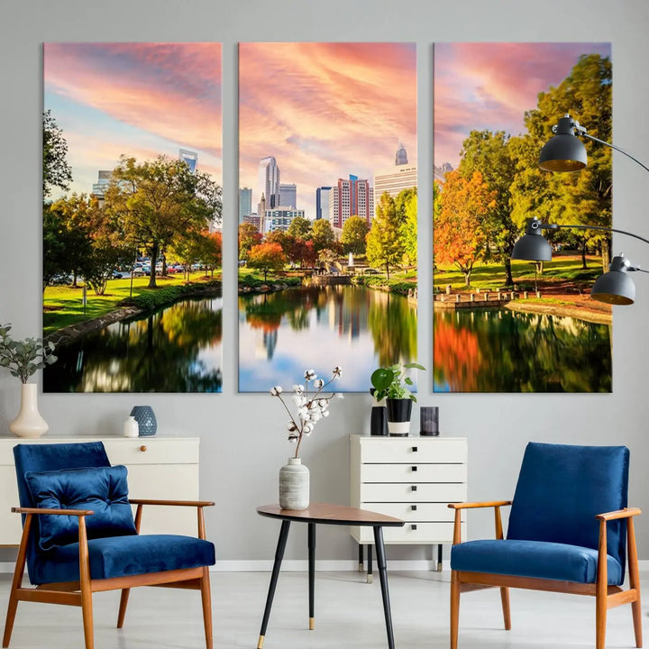 The "Charlotte City Park Sunset Pink and Orange Skyline Canvas Print" is elegantly displayed in a modern living room. Crafted on museum-quality canvas, this triptych wall art showcases a cityscape and park at sunset, complete with a UV-protective coating, and is ready to hang.