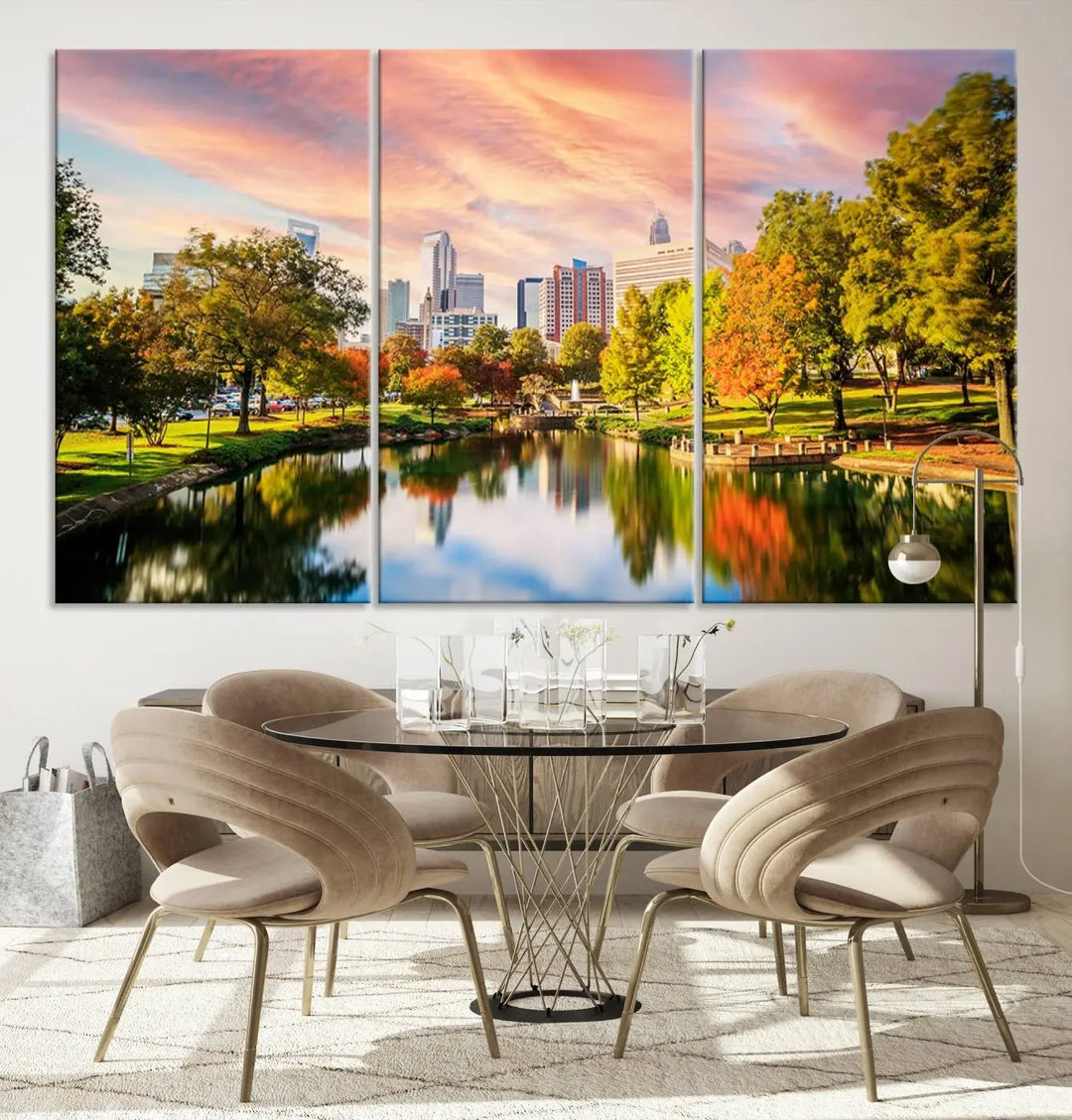 The "Charlotte City Park Sunset Pink and Orange Skyline Canvas Print" is elegantly displayed in a modern living room. Crafted on museum-quality canvas, this triptych wall art showcases a cityscape and park at sunset, complete with a UV-protective coating, and is ready to hang.