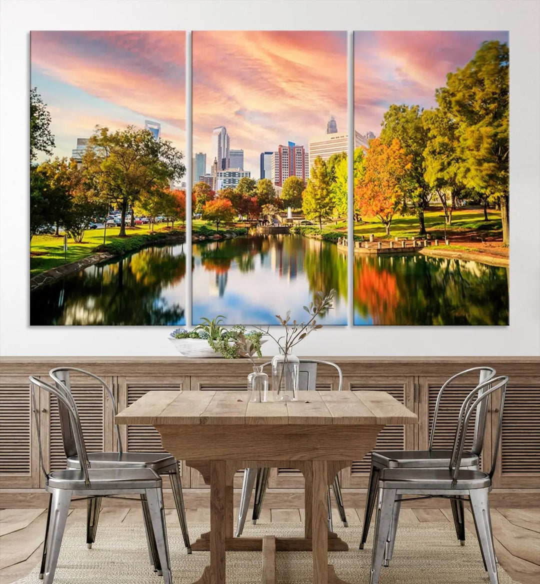 The "Charlotte City Park Sunset Pink and Orange Skyline Canvas Print" is elegantly displayed in a modern living room. Crafted on museum-quality canvas, this triptych wall art showcases a cityscape and park at sunset, complete with a UV-protective coating, and is ready to hang.