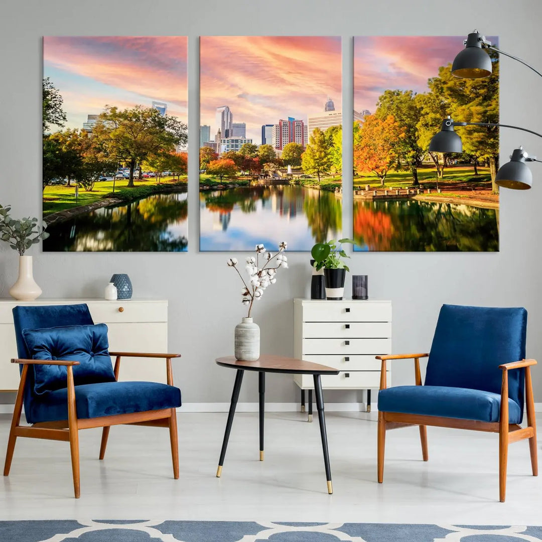 The "Charlotte City Park Sunset Pink and Orange Skyline Canvas Print" is elegantly displayed in a modern living room. Crafted on museum-quality canvas, this triptych wall art showcases a cityscape and park at sunset, complete with a UV-protective coating, and is ready to hang.