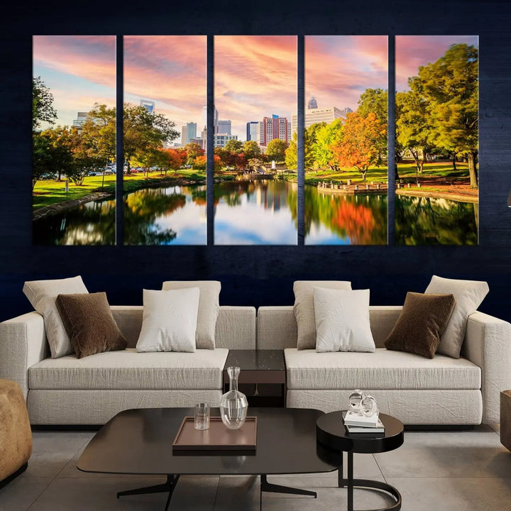 The "Charlotte City Park Sunset Pink and Orange Skyline Canvas Print" is elegantly displayed in a modern living room. Crafted on museum-quality canvas, this triptych wall art showcases a cityscape and park at sunset, complete with a UV-protective coating, and is ready to hang.