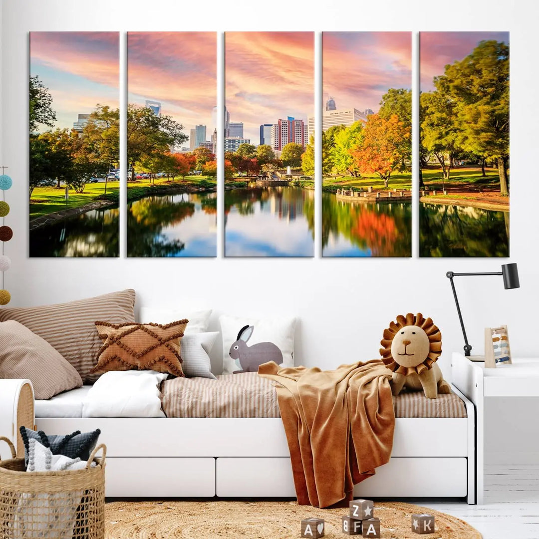 The "Charlotte City Park Sunset Pink and Orange Skyline Canvas Print" is elegantly displayed in a modern living room. Crafted on museum-quality canvas, this triptych wall art showcases a cityscape and park at sunset, complete with a UV-protective coating, and is ready to hang.