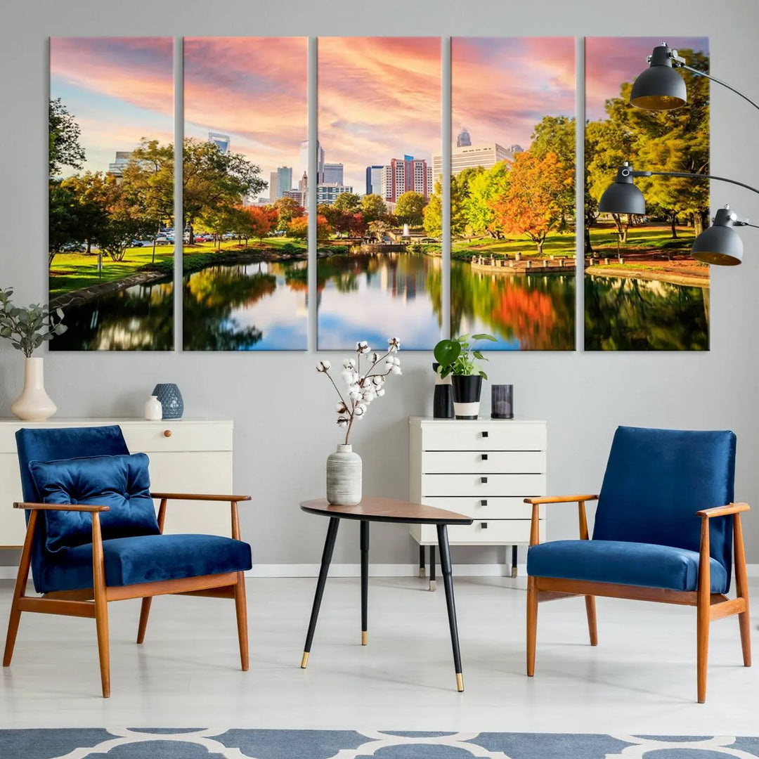 The "Charlotte City Park Sunset Pink and Orange Skyline Canvas Print" is elegantly displayed in a modern living room. Crafted on museum-quality canvas, this triptych wall art showcases a cityscape and park at sunset, complete with a UV-protective coating, and is ready to hang.