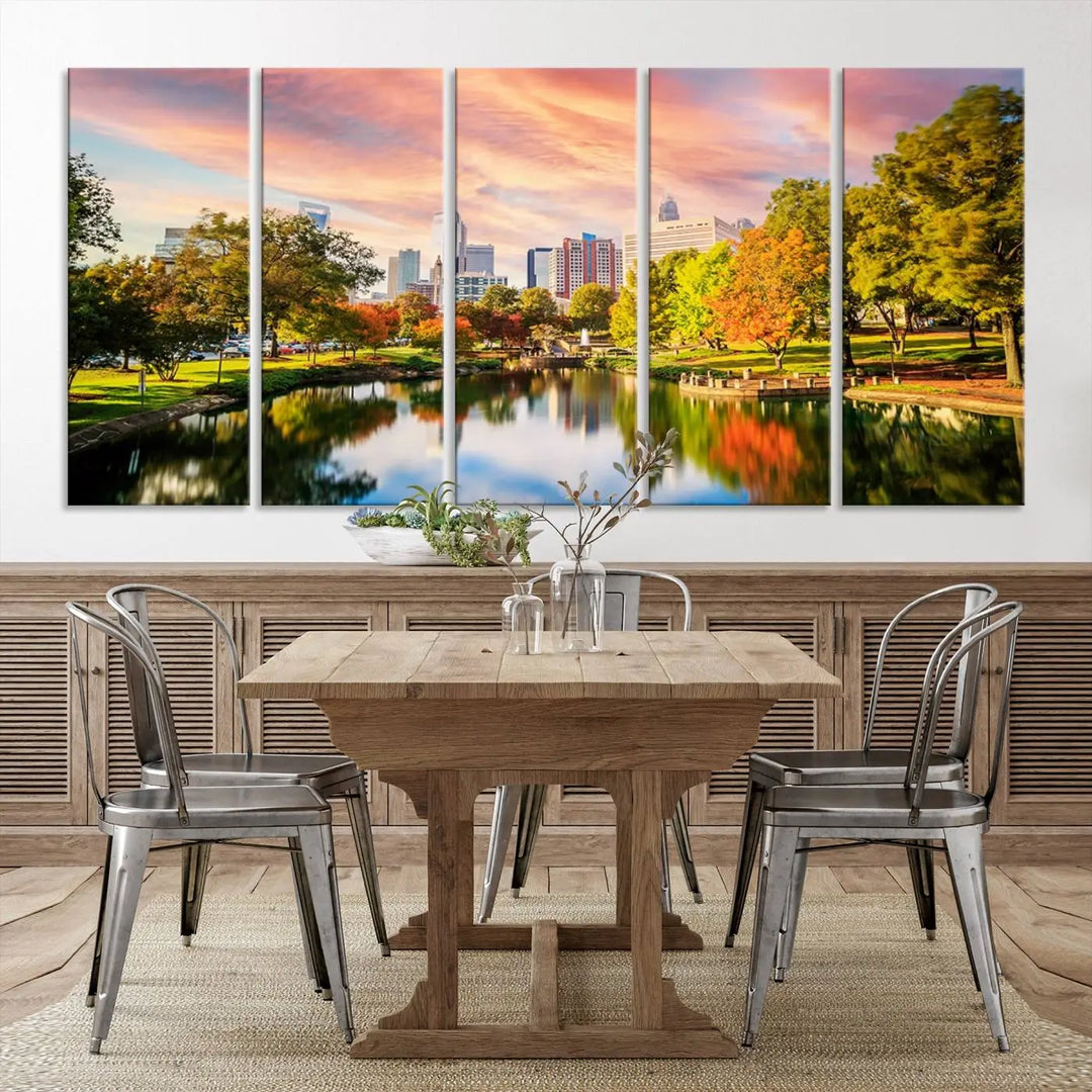 The "Charlotte City Park Sunset Pink and Orange Skyline Canvas Print" is elegantly displayed in a modern living room. Crafted on museum-quality canvas, this triptych wall art showcases a cityscape and park at sunset, complete with a UV-protective coating, and is ready to hang.