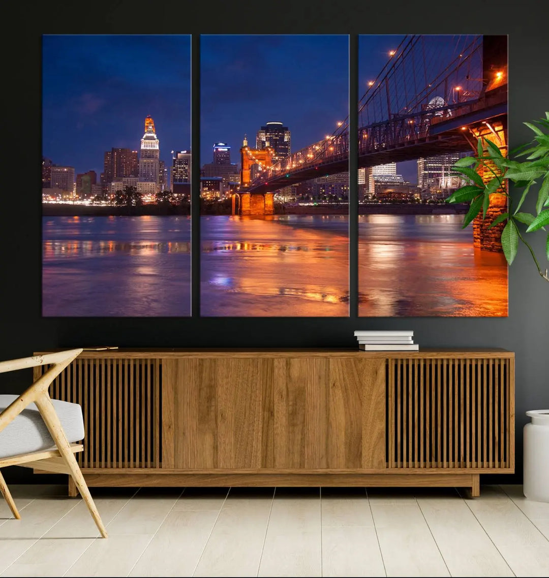 The Cincinnati City Bridge Lights Night Skyline Cityscape View Wall Art Canvas Print is a magnificent triptych crafted on museum-quality polycotton canvas. It features a beautifully illuminated bridge over water at night, enhancing any living room with its elegant design.