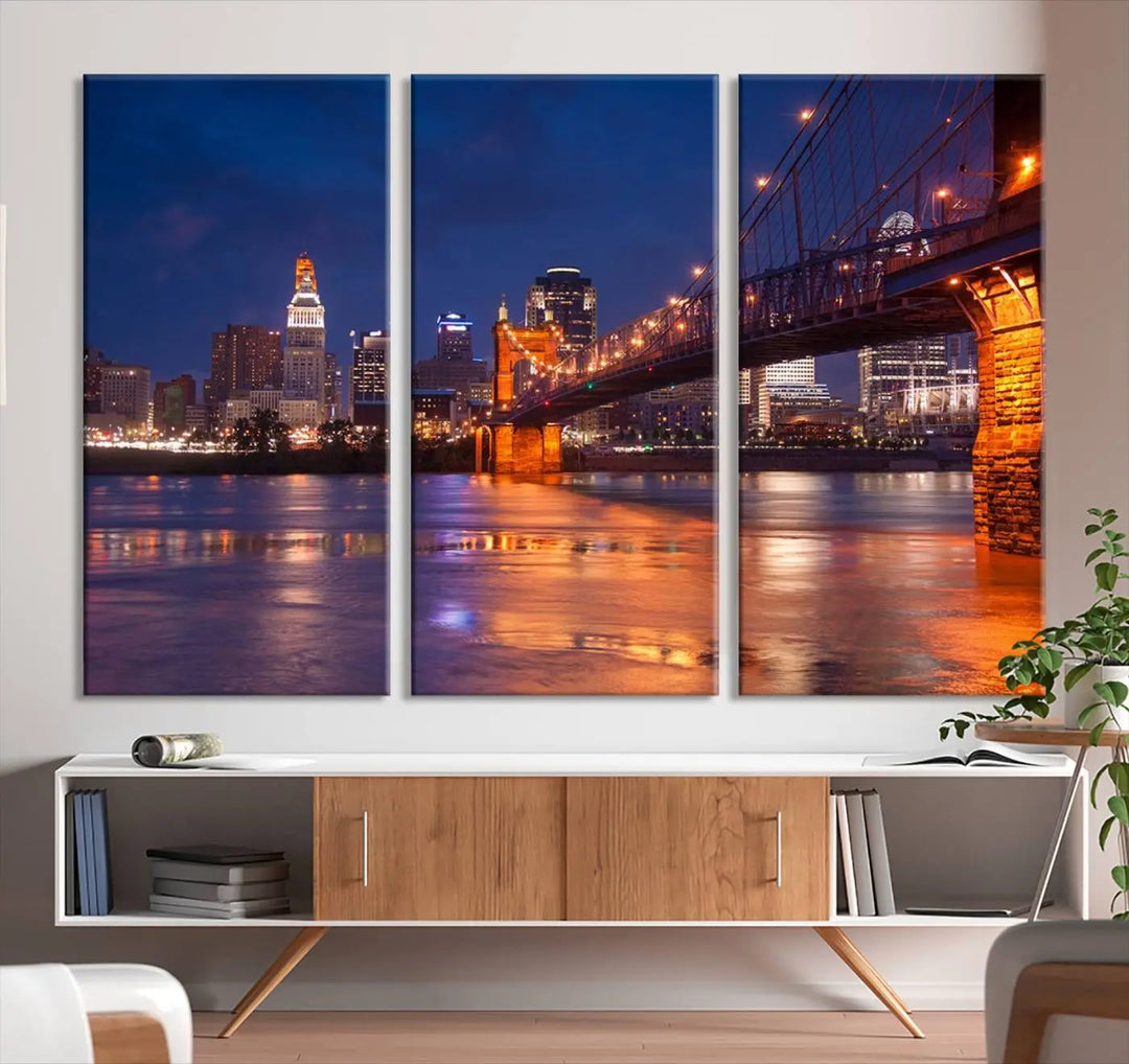 The Cincinnati City Bridge Lights Night Skyline Cityscape View Wall Art Canvas Print is a magnificent triptych crafted on museum-quality polycotton canvas. It features a beautifully illuminated bridge over water at night, enhancing any living room with its elegant design.