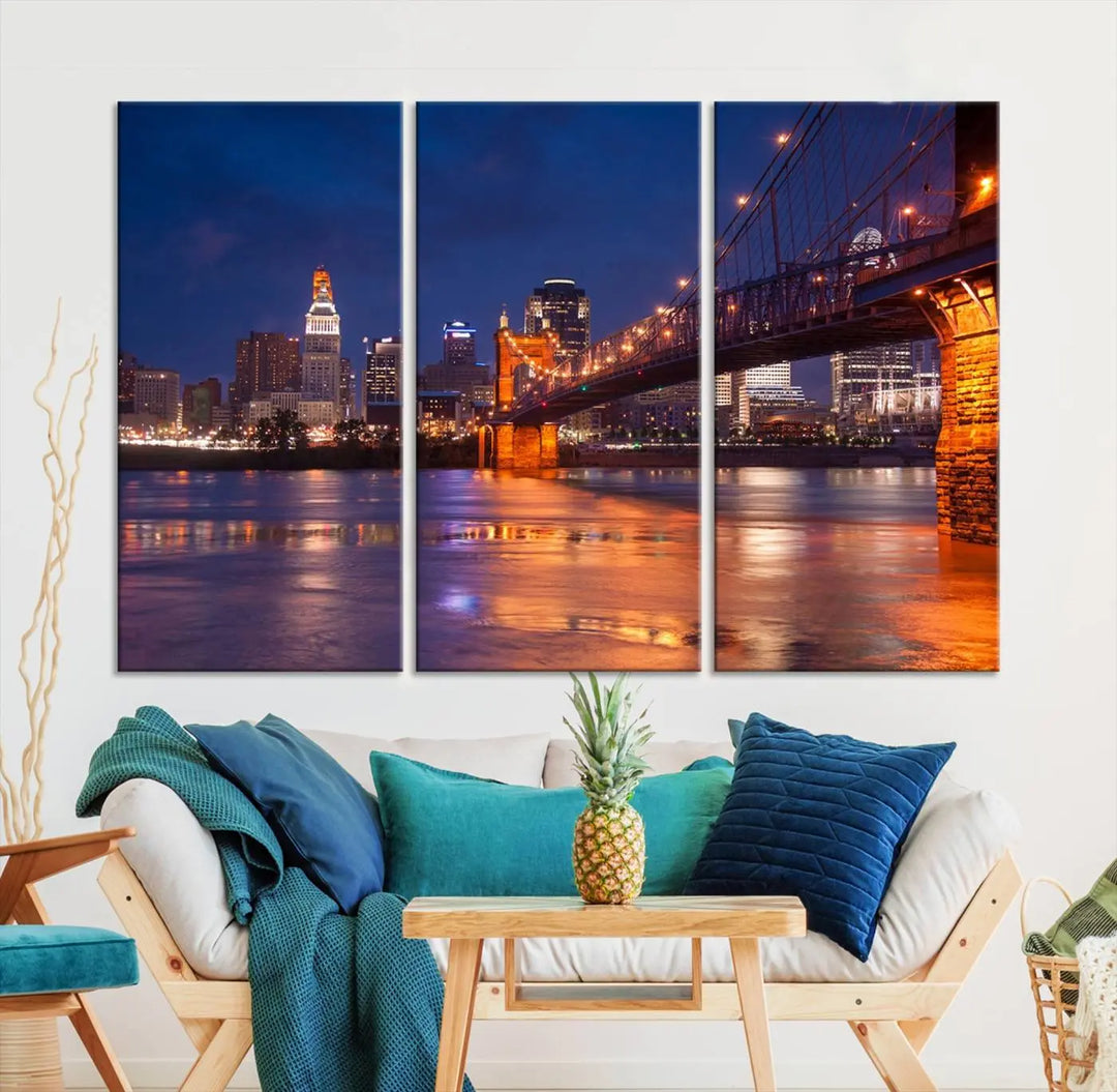 The Cincinnati City Bridge Lights Night Skyline Cityscape View Wall Art Canvas Print is a magnificent triptych crafted on museum-quality polycotton canvas. It features a beautifully illuminated bridge over water at night, enhancing any living room with its elegant design.