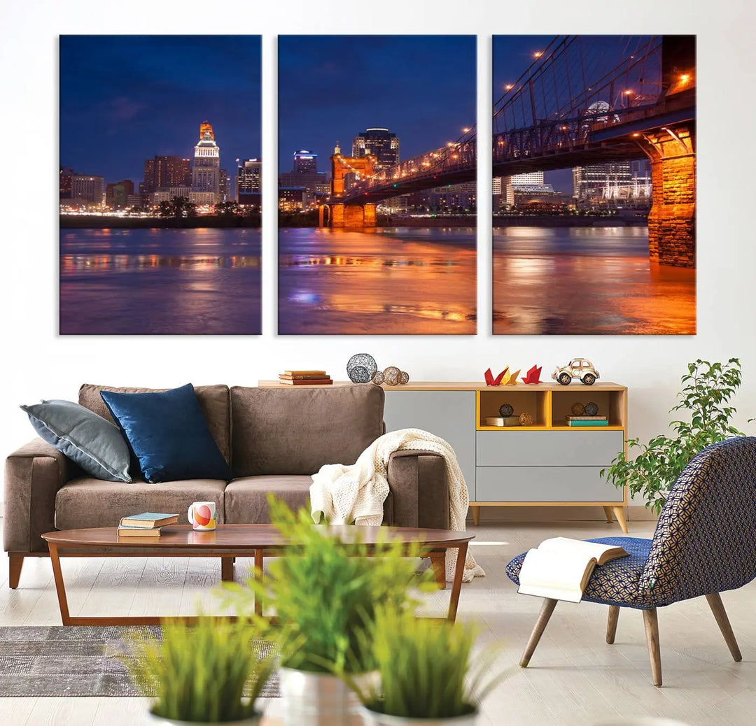 The Cincinnati City Bridge Lights Night Skyline Cityscape View Wall Art Canvas Print is a magnificent triptych crafted on museum-quality polycotton canvas. It features a beautifully illuminated bridge over water at night, enhancing any living room with its elegant design.