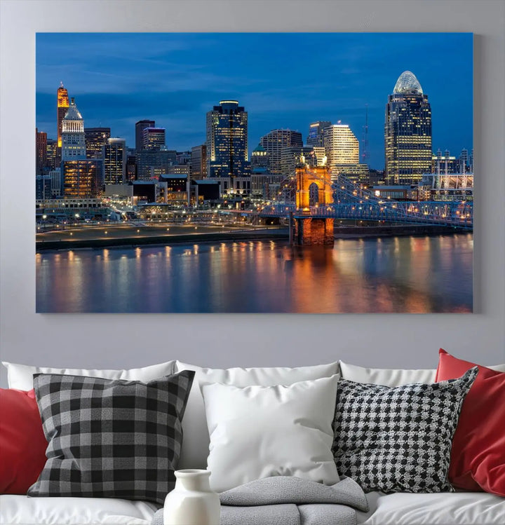 A triptych of the Cincinnati city lights night skyline, printed on museum-quality canvas with a UV-protective coating, hangs prominently on the wall.