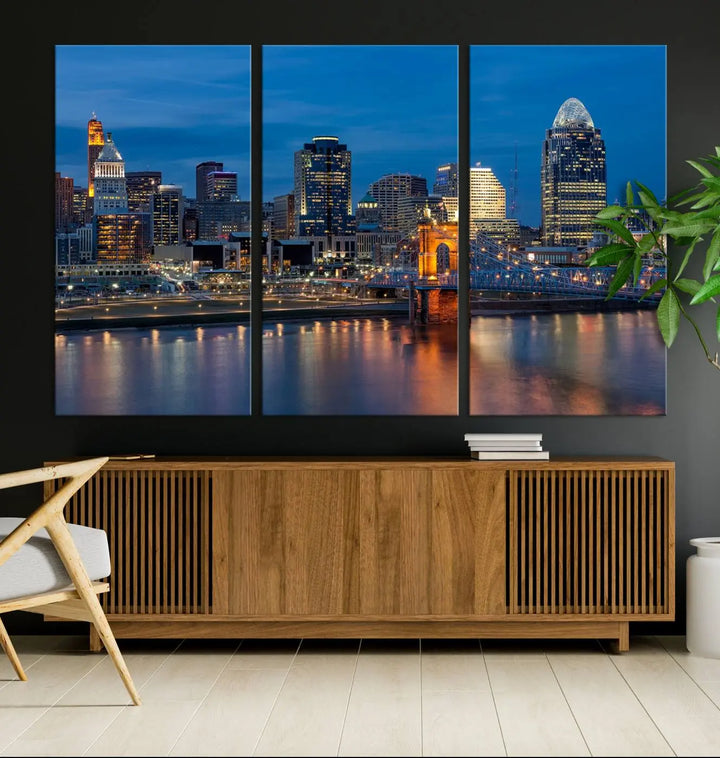 A triptych of the Cincinnati city lights night skyline, printed on museum-quality canvas with a UV-protective coating, hangs prominently on the wall.