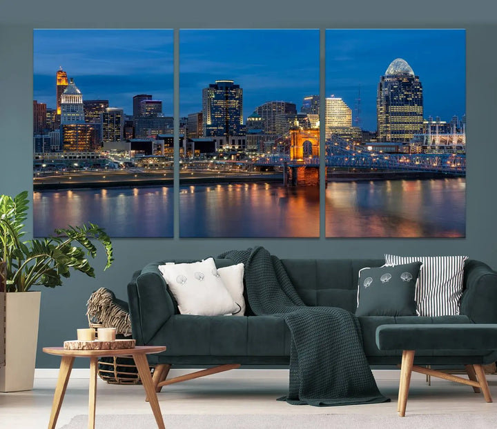 A triptych of the Cincinnati city lights night skyline, printed on museum-quality canvas with a UV-protective coating, hangs prominently on the wall.