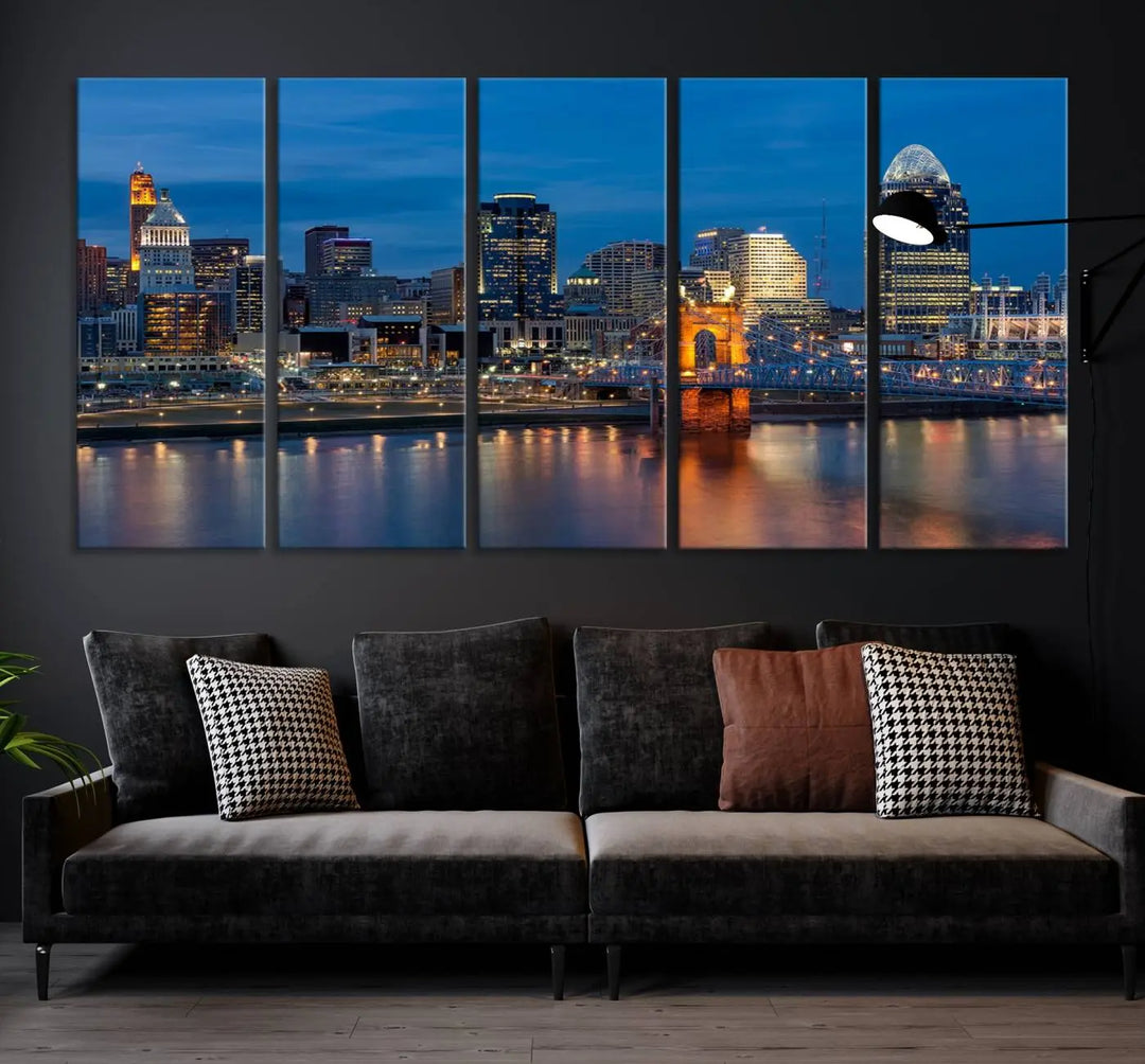 A triptych of the Cincinnati city lights night skyline, printed on museum-quality canvas with a UV-protective coating, hangs prominently on the wall.