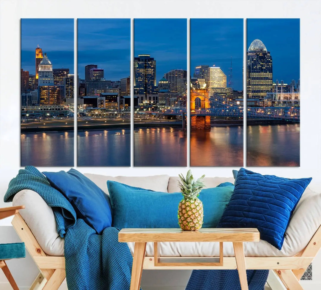 A triptych of the Cincinnati city lights night skyline, printed on museum-quality canvas with a UV-protective coating, hangs prominently on the wall.