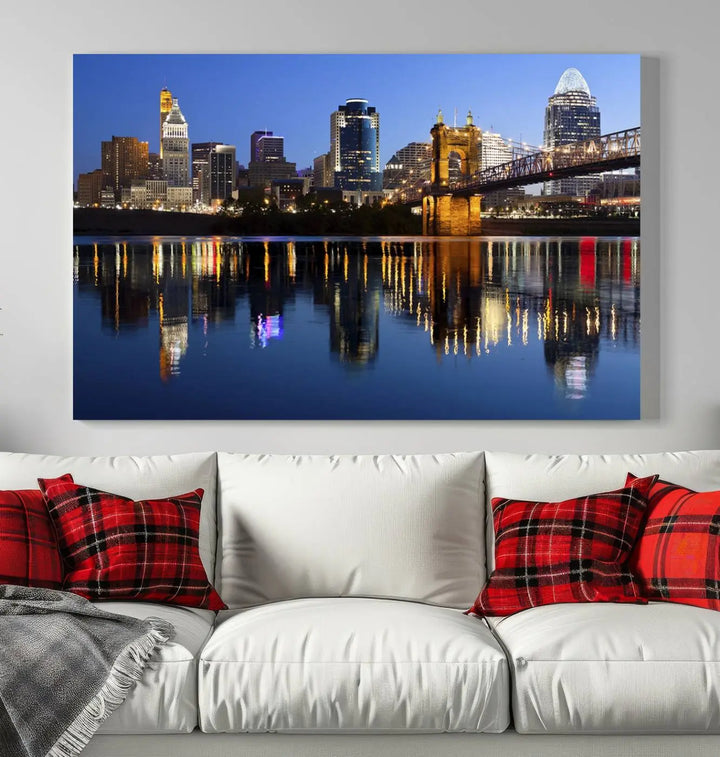 The Cincinnati City Lights Night Skyline Cityscape View Wall Art Canvas Print showcases a cityscape at night reflecting on water. It is crafted on museum-quality canvases with a UV-protective coating.