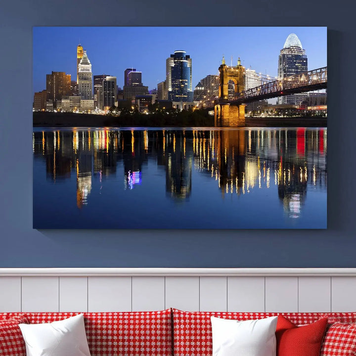 The Cincinnati City Lights Night Skyline Cityscape View Wall Art Canvas Print showcases a cityscape at night reflecting on water. It is crafted on museum-quality canvases with a UV-protective coating.