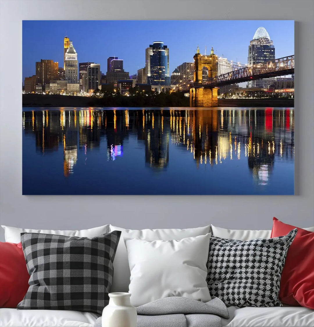 The Cincinnati City Lights Night Skyline Cityscape View Wall Art Canvas Print showcases a cityscape at night reflecting on water. It is crafted on museum-quality canvases with a UV-protective coating.