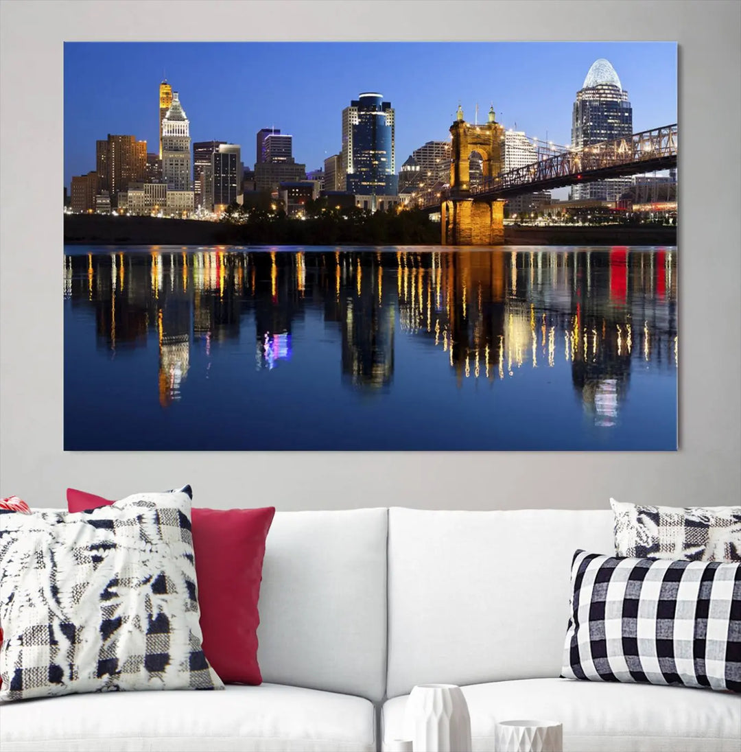 The Cincinnati City Lights Night Skyline Cityscape View Wall Art Canvas Print showcases a cityscape at night reflecting on water. It is crafted on museum-quality canvases with a UV-protective coating.