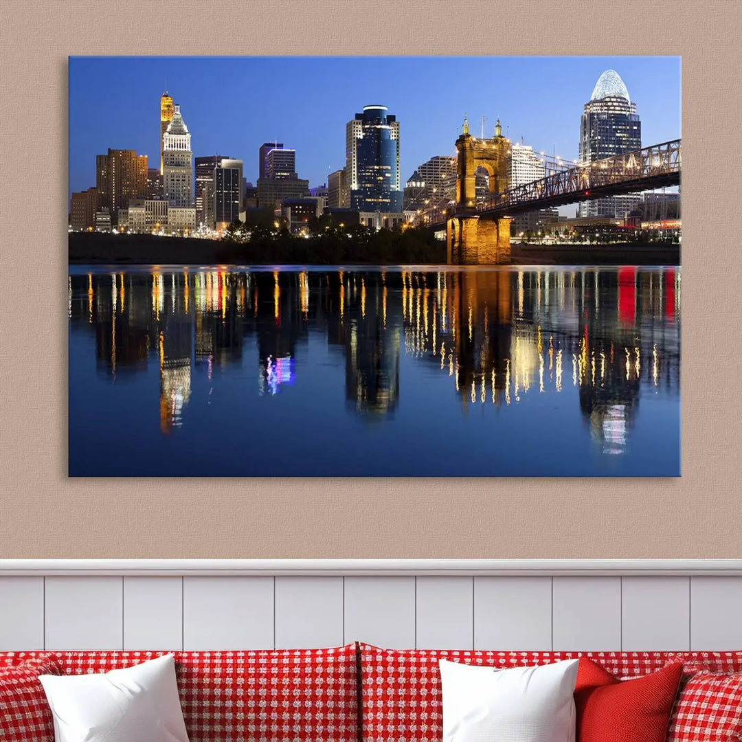 The Cincinnati City Lights Night Skyline Cityscape View Wall Art Canvas Print showcases a cityscape at night reflecting on water. It is crafted on museum-quality canvases with a UV-protective coating.