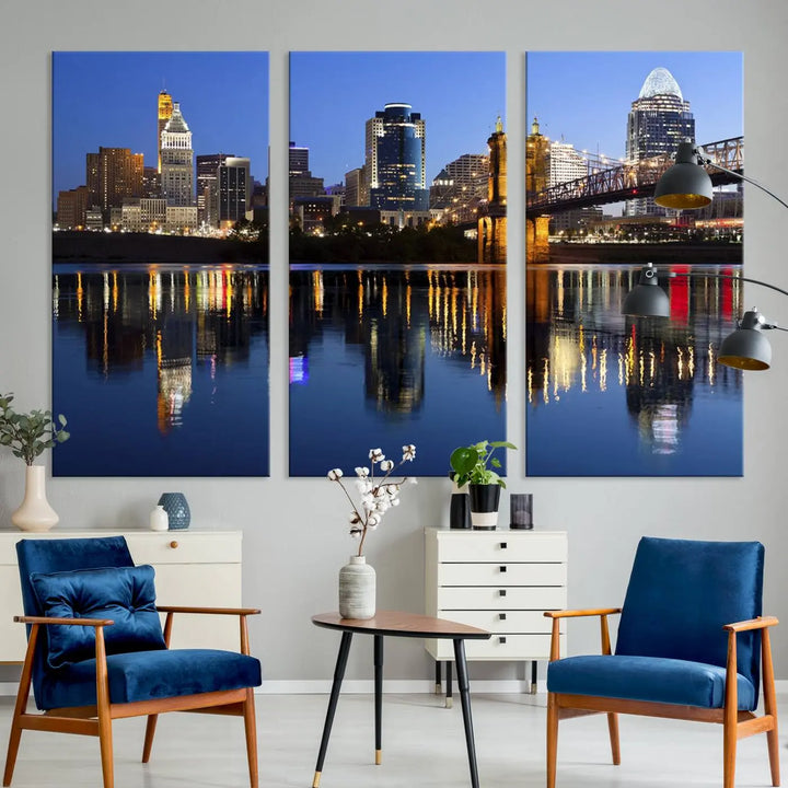 The Cincinnati City Lights Night Skyline Cityscape View Wall Art Canvas Print showcases a cityscape at night reflecting on water. It is crafted on museum-quality canvases with a UV-protective coating.