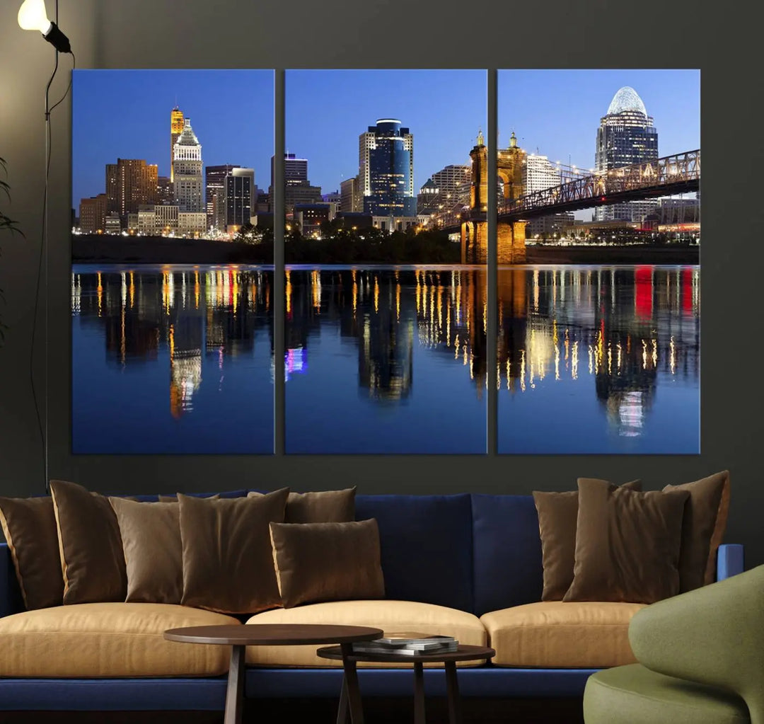 The Cincinnati City Lights Night Skyline Cityscape View Wall Art Canvas Print showcases a cityscape at night reflecting on water. It is crafted on museum-quality canvases with a UV-protective coating.