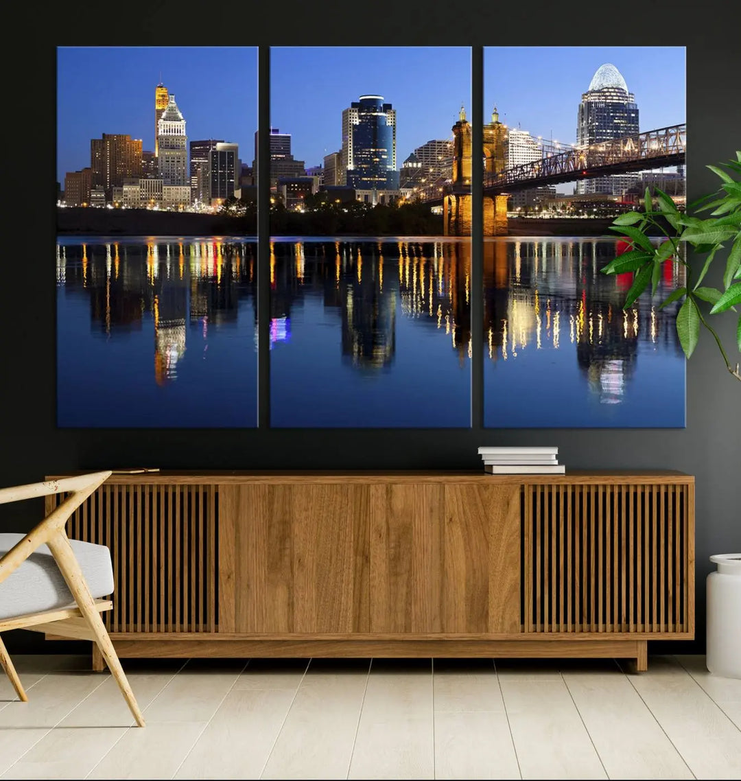 The Cincinnati City Lights Night Skyline Cityscape View Wall Art Canvas Print showcases a cityscape at night reflecting on water. It is crafted on museum-quality canvases with a UV-protective coating.