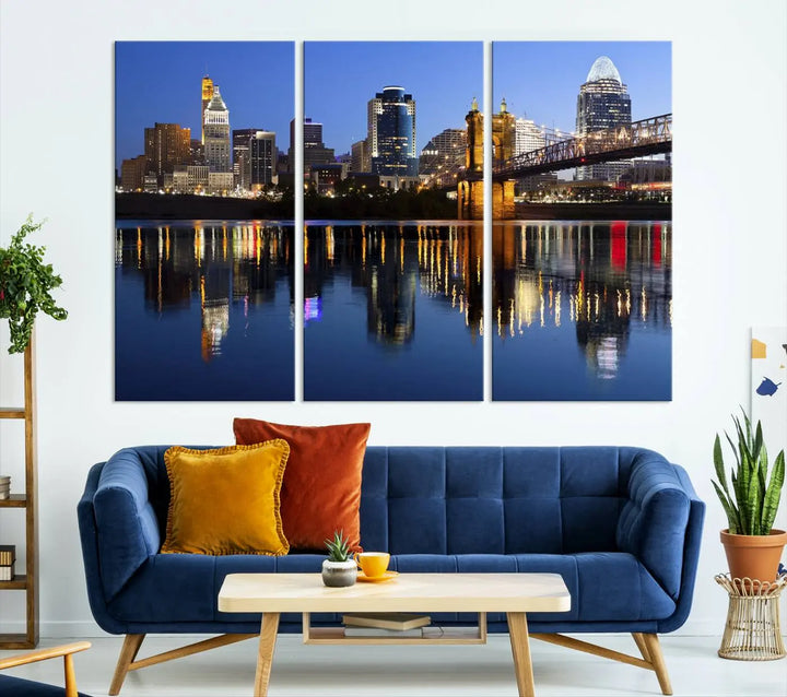 The Cincinnati City Lights Night Skyline Cityscape View Wall Art Canvas Print showcases a cityscape at night reflecting on water. It is crafted on museum-quality canvases with a UV-protective coating.