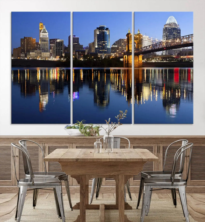 The Cincinnati City Lights Night Skyline Cityscape View Wall Art Canvas Print showcases a cityscape at night reflecting on water. It is crafted on museum-quality canvases with a UV-protective coating.