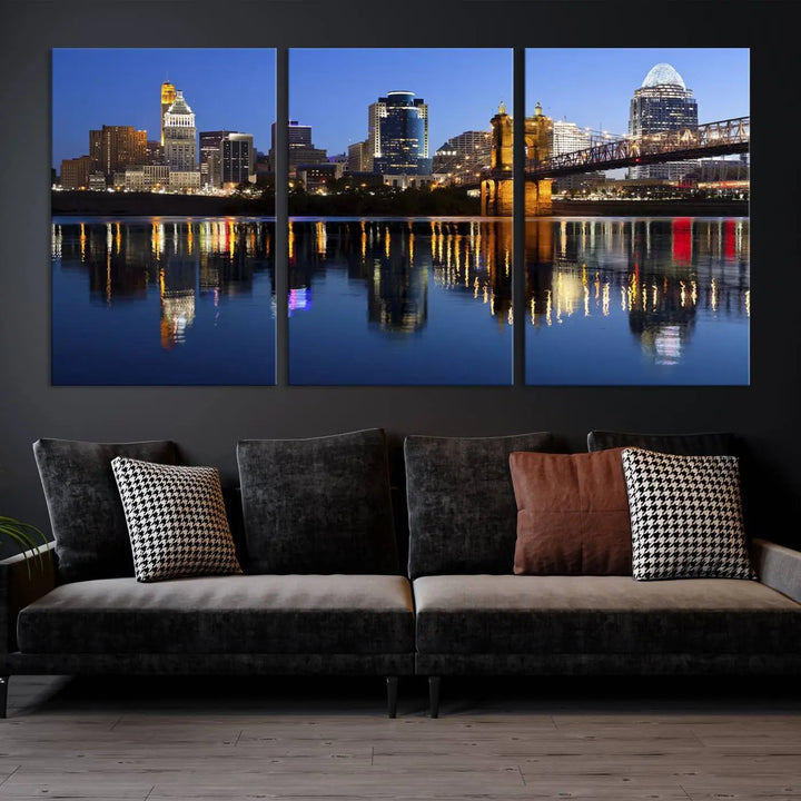 The Cincinnati City Lights Night Skyline Cityscape View Wall Art Canvas Print showcases a cityscape at night reflecting on water. It is crafted on museum-quality canvases with a UV-protective coating.