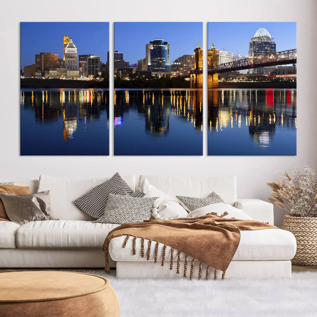 The Cincinnati City Lights Night Skyline Cityscape View Wall Art Canvas Print showcases a cityscape at night reflecting on water. It is crafted on museum-quality canvases with a UV-protective coating.