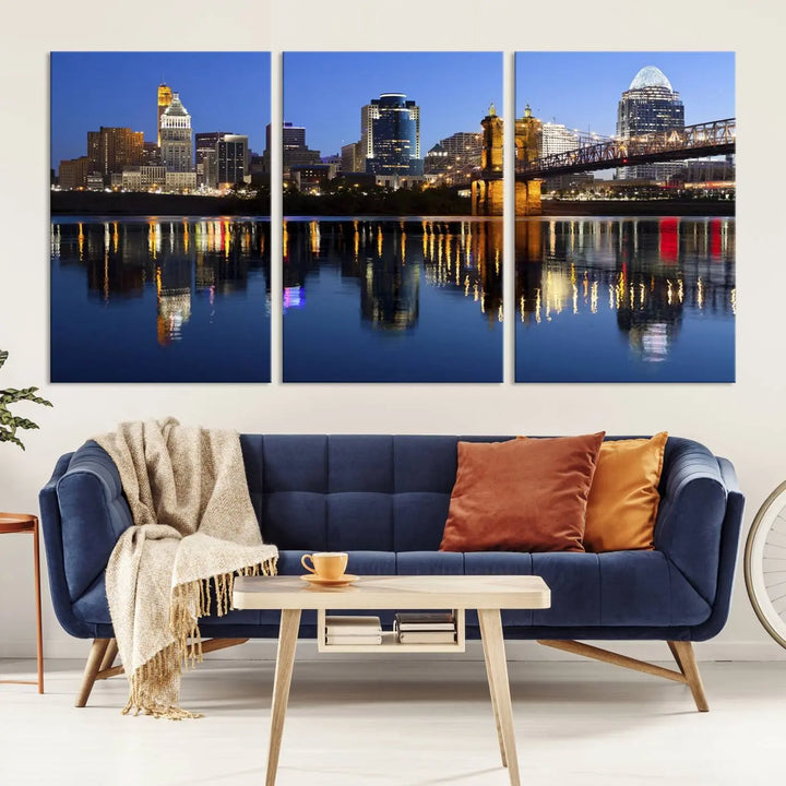 The Cincinnati City Lights Night Skyline Cityscape View Wall Art Canvas Print showcases a cityscape at night reflecting on water. It is crafted on museum-quality canvases with a UV-protective coating.