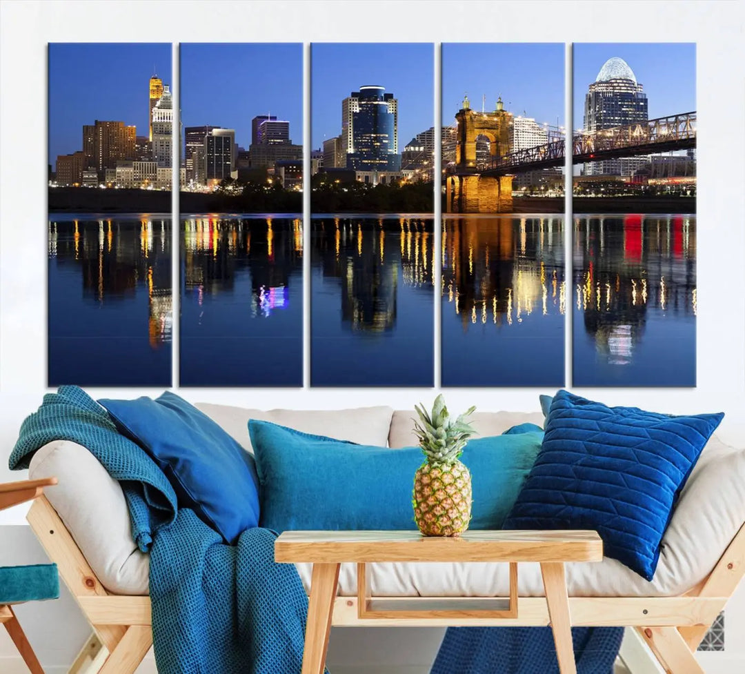 The Cincinnati City Lights Night Skyline Cityscape View Wall Art Canvas Print showcases a cityscape at night reflecting on water. It is crafted on museum-quality canvases with a UV-protective coating.