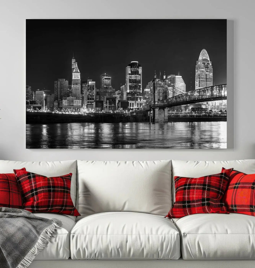 The Cincinnati City Lights Skyline Black and White Wall Art Cityscape Canvas Print elegantly adorns a modern living room. This museum-quality canvas triptych of a city skyline is enhanced by hand-assembled frames for added finesse, and you can enjoy free shipping on this stunning home addition.