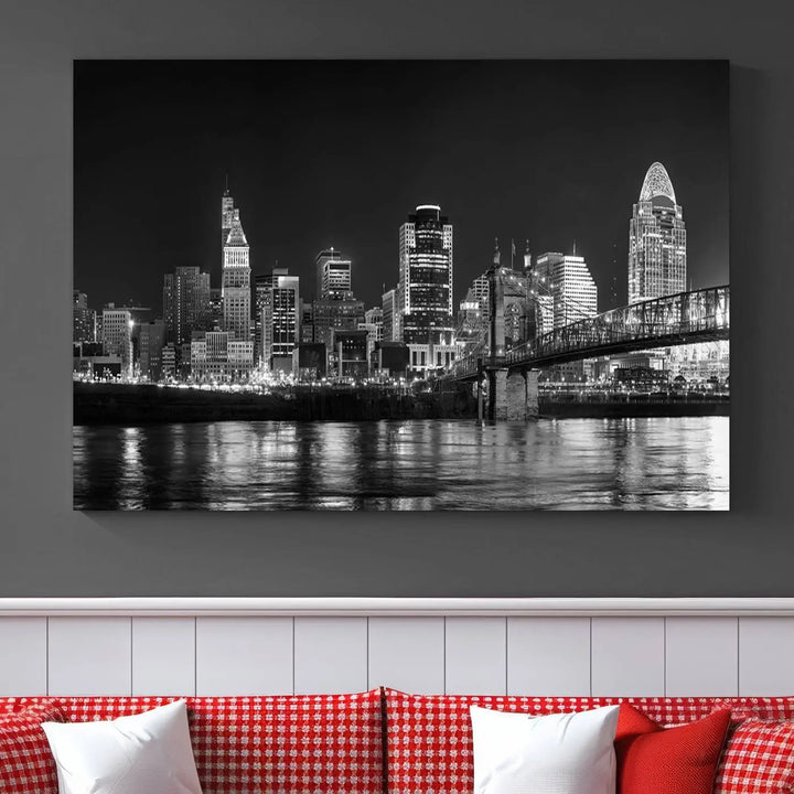 The Cincinnati City Lights Skyline Black and White Wall Art Cityscape Canvas Print elegantly adorns a modern living room. This museum-quality canvas triptych of a city skyline is enhanced by hand-assembled frames for added finesse, and you can enjoy free shipping on this stunning home addition.