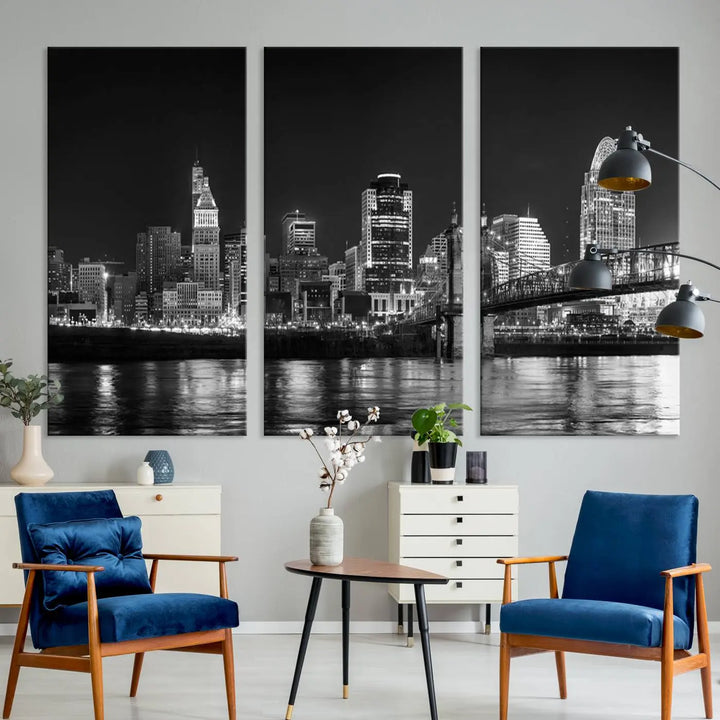 The Cincinnati City Lights Skyline Black and White Wall Art Cityscape Canvas Print elegantly adorns a modern living room. This museum-quality canvas triptych of a city skyline is enhanced by hand-assembled frames for added finesse, and you can enjoy free shipping on this stunning home addition.