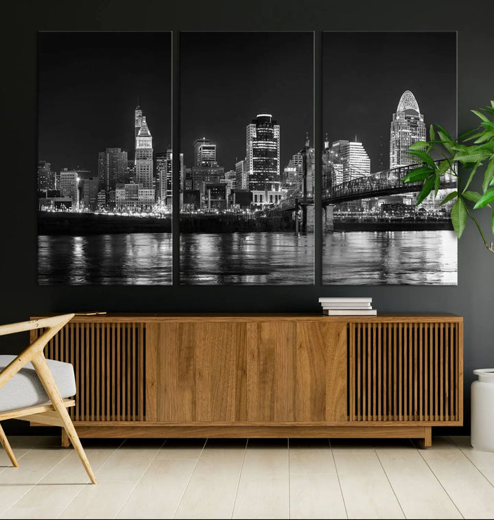 The Cincinnati City Lights Skyline Black and White Wall Art Cityscape Canvas Print elegantly adorns a modern living room. This museum-quality canvas triptych of a city skyline is enhanced by hand-assembled frames for added finesse, and you can enjoy free shipping on this stunning home addition.