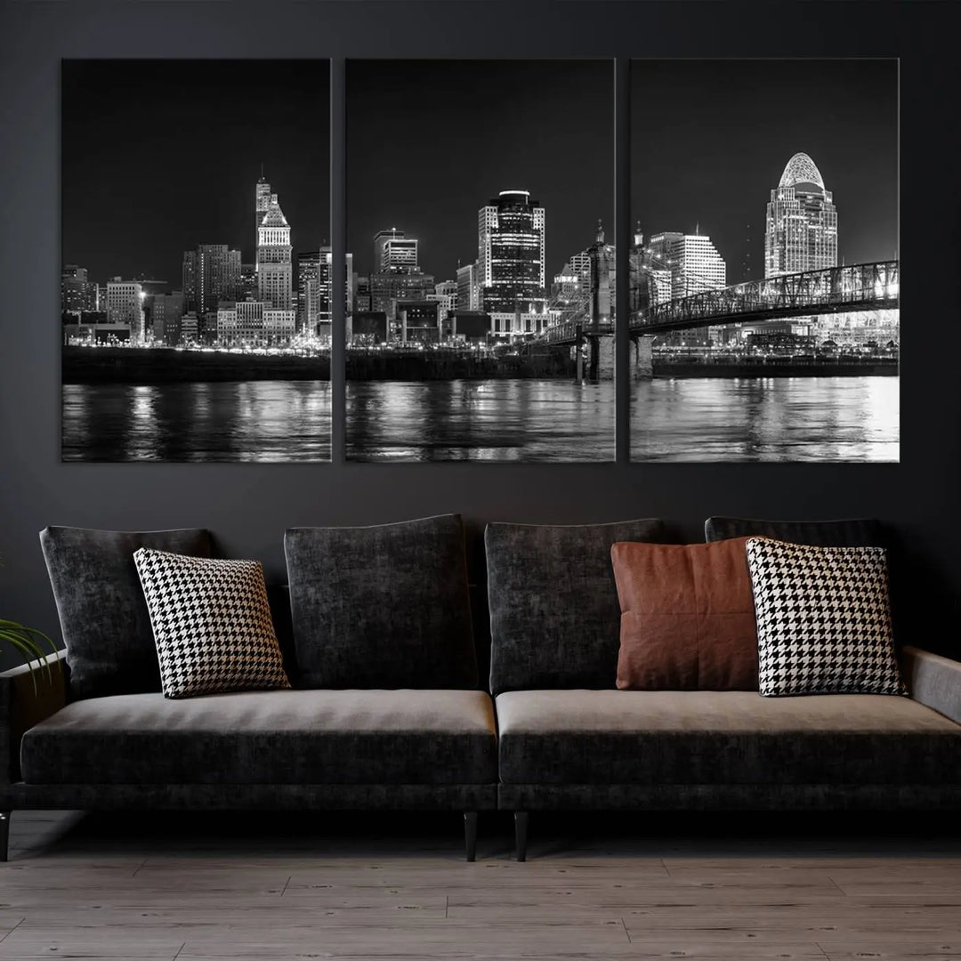 The Cincinnati City Lights Skyline Black and White Wall Art Cityscape Canvas Print elegantly adorns a modern living room. This museum-quality canvas triptych of a city skyline is enhanced by hand-assembled frames for added finesse, and you can enjoy free shipping on this stunning home addition.