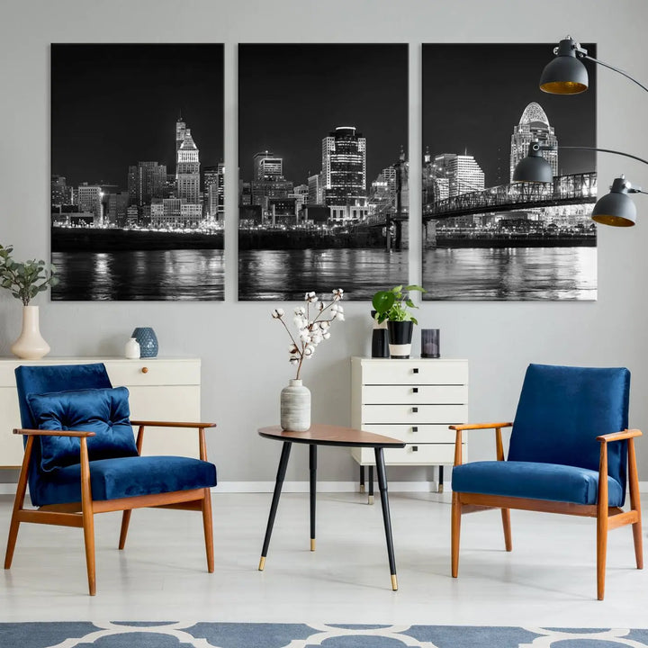 The Cincinnati City Lights Skyline Black and White Wall Art Cityscape Canvas Print elegantly adorns a modern living room. This museum-quality canvas triptych of a city skyline is enhanced by hand-assembled frames for added finesse, and you can enjoy free shipping on this stunning home addition.