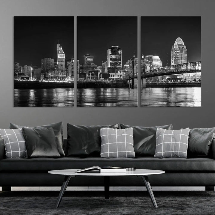 The Cincinnati City Lights Skyline Black and White Wall Art Cityscape Canvas Print elegantly adorns a modern living room. This museum-quality canvas triptych of a city skyline is enhanced by hand-assembled frames for added finesse, and you can enjoy free shipping on this stunning home addition.