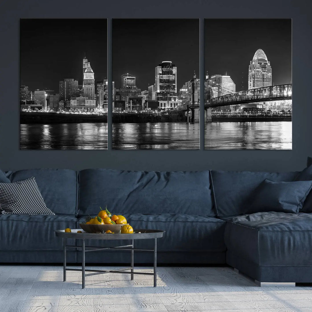 The Cincinnati City Lights Skyline Black and White Wall Art Cityscape Canvas Print elegantly adorns a modern living room. This museum-quality canvas triptych of a city skyline is enhanced by hand-assembled frames for added finesse, and you can enjoy free shipping on this stunning home addition.