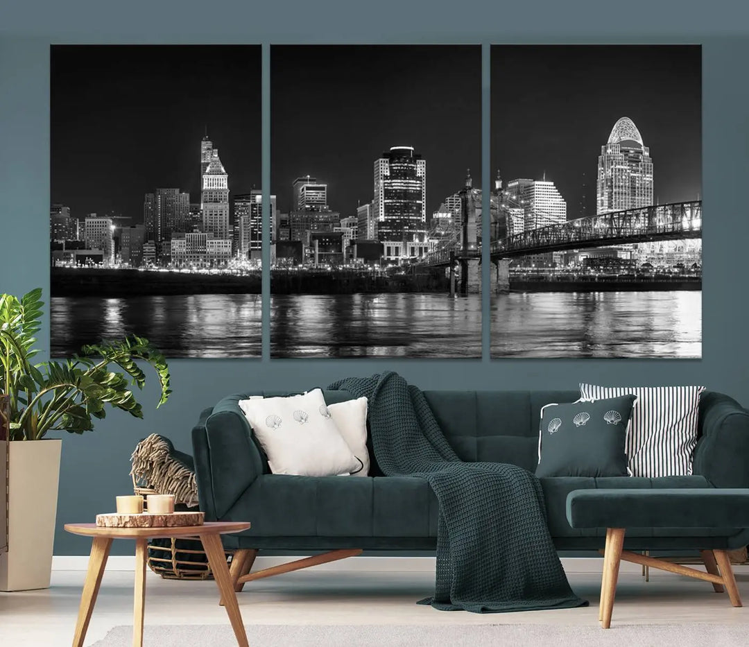 The Cincinnati City Lights Skyline Black and White Wall Art Cityscape Canvas Print elegantly adorns a modern living room. This museum-quality canvas triptych of a city skyline is enhanced by hand-assembled frames for added finesse, and you can enjoy free shipping on this stunning home addition.