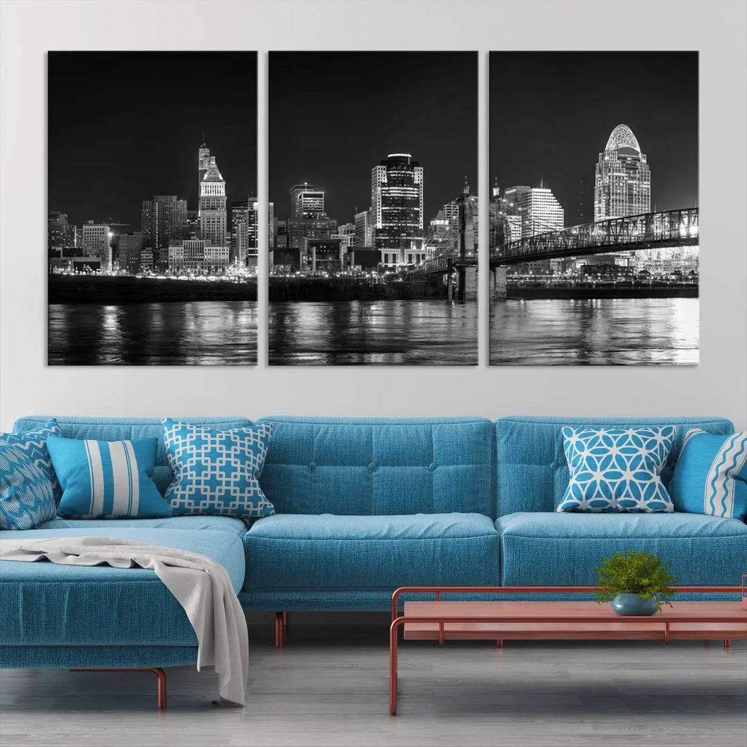 The Cincinnati City Lights Skyline Black and White Wall Art Cityscape Canvas Print elegantly adorns a modern living room. This museum-quality canvas triptych of a city skyline is enhanced by hand-assembled frames for added finesse, and you can enjoy free shipping on this stunning home addition.