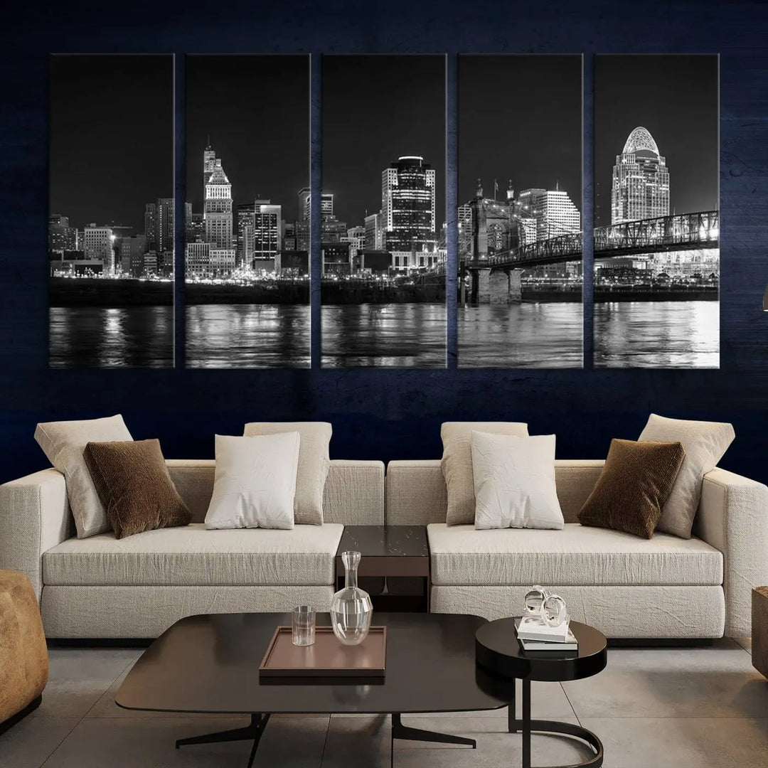 The Cincinnati City Lights Skyline Black and White Wall Art Cityscape Canvas Print elegantly adorns a modern living room. This museum-quality canvas triptych of a city skyline is enhanced by hand-assembled frames for added finesse, and you can enjoy free shipping on this stunning home addition.